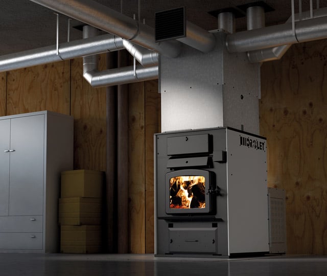 Wood furnace installed in a basement, with visible metal ductwork extending from the furnace to distribute heat.