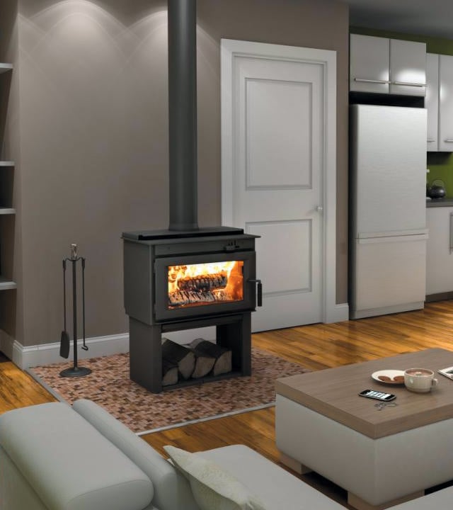 Modern living room with a wood-burning stove radiating warmth, placed on a tiled hearth mat. The stove has logs burning inside, with extra logs stored underneath. 